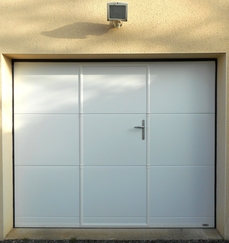 Porte sectionnelle plafond avec portillon modèle MAORI - dimensions baie : ht 1990mm x largeur 2380mm - structure monobloc - manœuvre électrique - 2 émetteurs 4 canaux - Panneau lisse coloris Blanc Satiné (RAL 9016) - Portillon à serrure multipoints et poignée aspect inox.